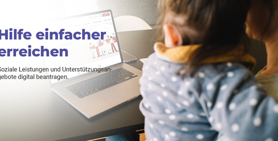 Person hält Kind auf den Schoss und beide schauen auf den Laptop, wo die Seite vom Sozialamt zu sehen ist.